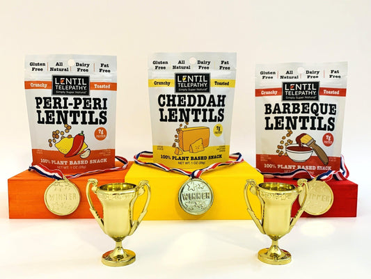 Podium stands featuring Lentil Telepathy snacks each with a gold medal and winner trophy to show why lentils win for nutrition and health benefits